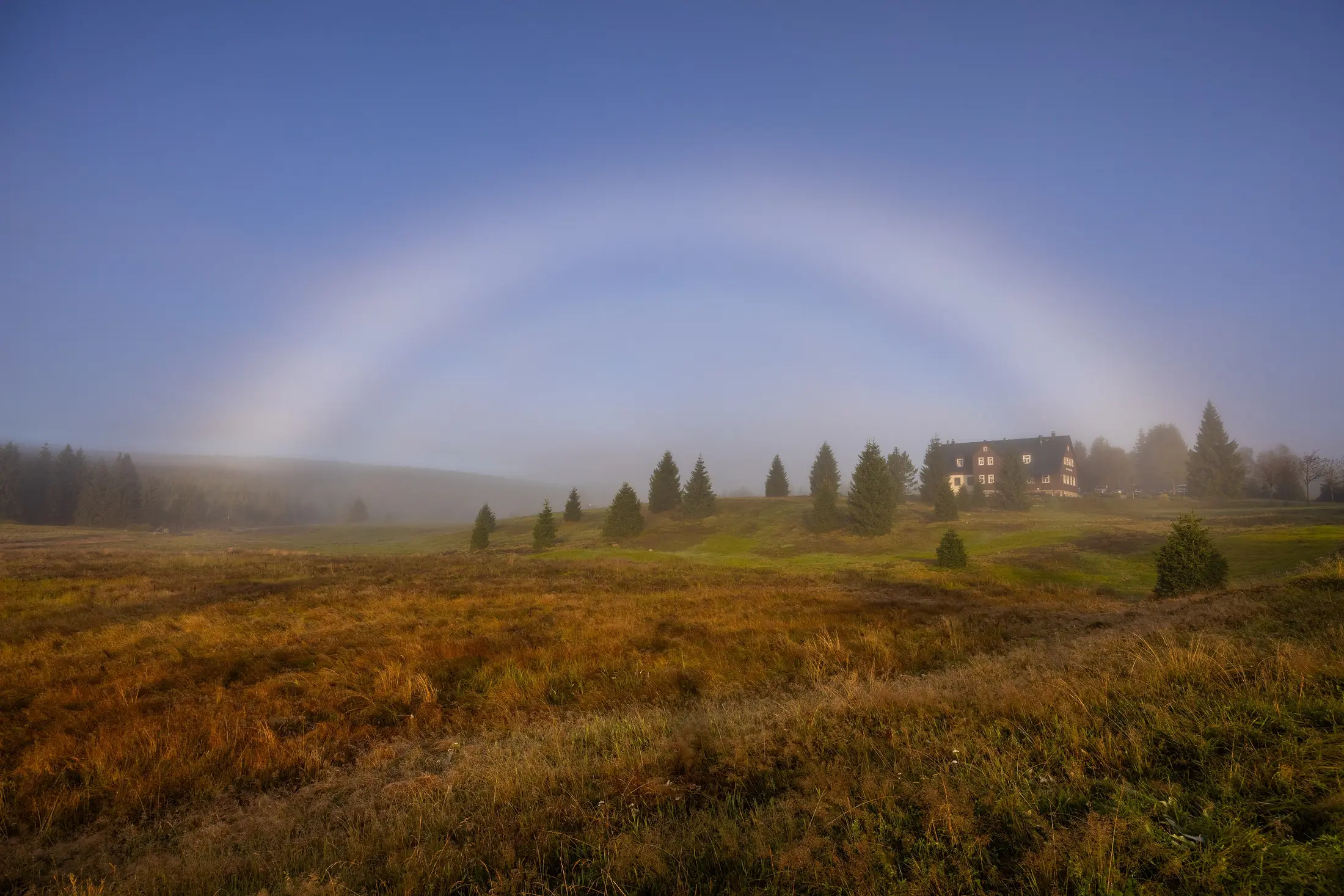 Mlžná duha nad podzimními loukami u Jizerky